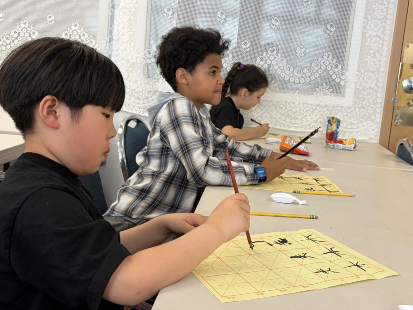 Two students work with brushes at a long table