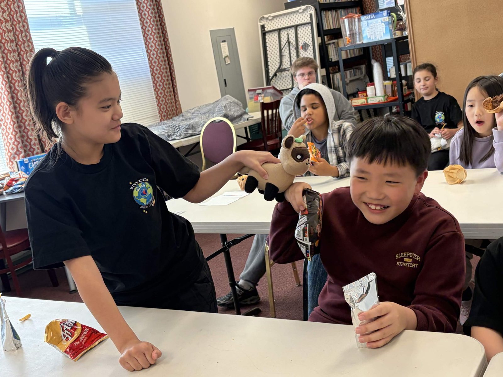 An older student helps a younger boy at the table