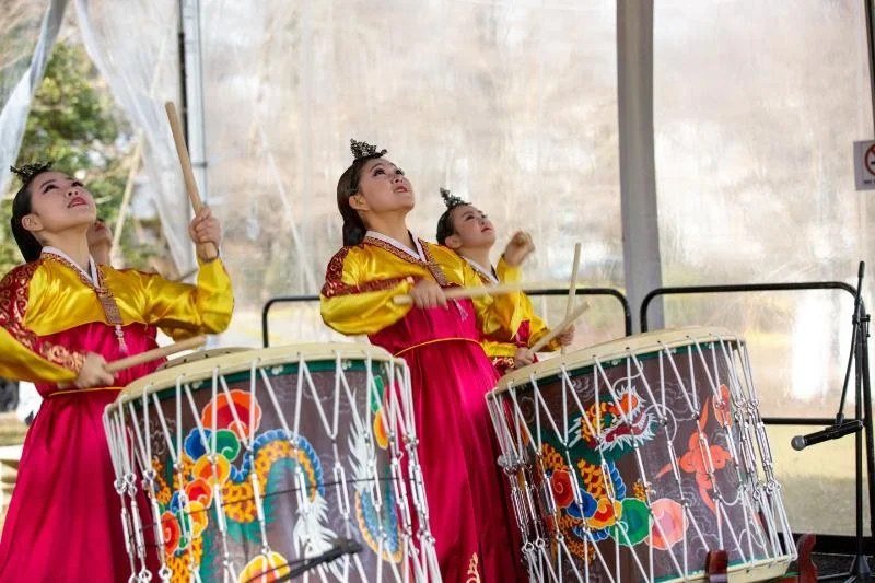 Two performers in traditional costume play drums
