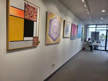 Paintings hung along a white gallery wall